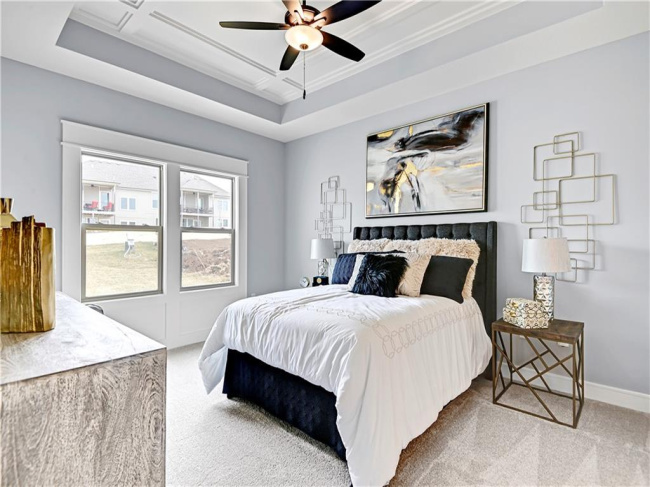 Carpeted bedroom featuring ceiling fan, a raised ceiling, ornamental molding, and coffered ceiling