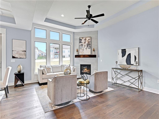 Living room featuring hardwood / wood-style floors, ceiling fan, a raised ceiling, and a fireplace