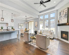 Living room featuring dark hardwood / wood-style flooring, a tray ceiling, ceiling fan, and a healthy amount of sunlight